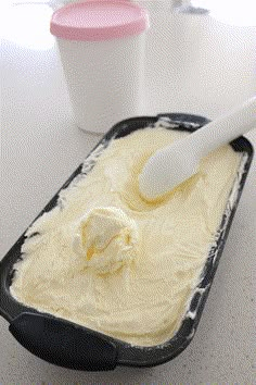 a scoop of ice cream in a black container with a white spoon on the side