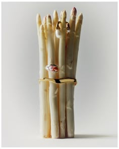 a group of white asparagus wrapped in gold ribbon with rings on top and pearls around the ends