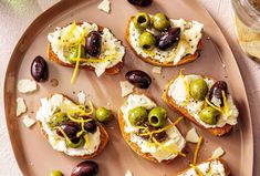 toasted bread topped with olives, cheese and other toppings on a plate