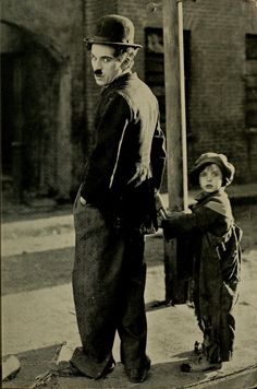 an old black and white photo of two children standing on the side of a street