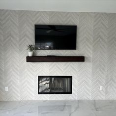 a tv mounted on the wall above a fireplace in a room with white marble flooring