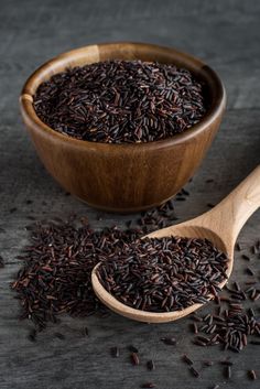 a wooden spoon filled with brown rice on top of a table