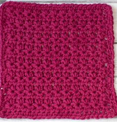 a pink crocheted dishcloth sitting on top of a white wooden table next to a pair of scissors