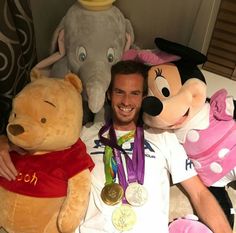 a man sitting in front of stuffed animals with medals around his neck and chest, smiling at the camera