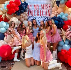 a group of young women standing next to each other in front of an american flag backdrop