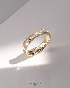 a yellow gold wedding ring with small diamonds on the inside and outside, sitting on a white surface