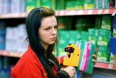 a woman in a red jacket is holding a yellow and black object while she looks at it