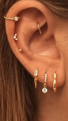 a woman wearing three different types of ear piercings