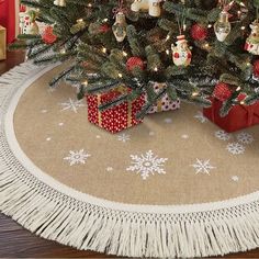 a christmas tree with presents under it on a rug in the middle of a room