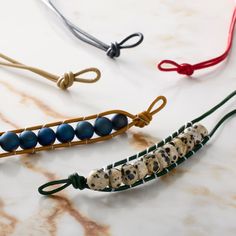 three different bracelets with beads on them sitting on a marble counter top next to each other