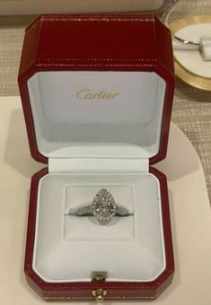 an engagement ring in a red box with the name cartier on it's side