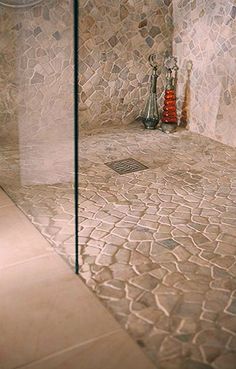 a bathroom with a glass shower door next to a tiled floor and walls, along with a vase in the corner