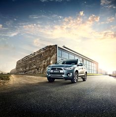 a silver suv parked in front of a building on the side of an empty road