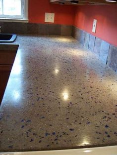 an empty kitchen with red walls and granite counter tops