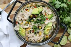 a glass bowl filled with guacamole, corn and avocado on top of a wooden cutting board