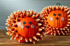 two pumpkins decorated like hedgehogs sitting on top of a wooden table