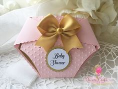 a pink box with a gold bow and name tag on it sitting on a lace doily