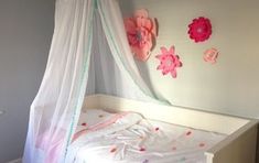 a child's bed with pink flowers on the headboard and canopy over it