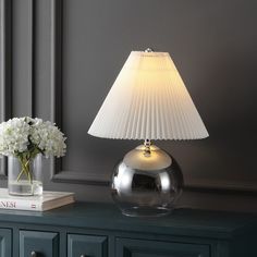 a lamp that is on top of a table next to a vase with flowers in it