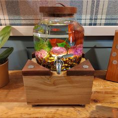 a fish bowl is sitting on top of a wooden box with some plants in it