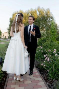 a man in a suit and tie walking next to a woman in a white dress