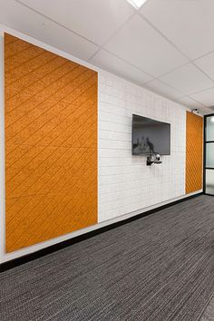 an empty room with orange and white walls, carpeted flooring and a flat screen tv mounted to the wall