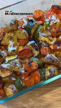 a glass casserole dish filled with potatoes and carrots on a wooden table