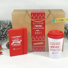 a red coffee cup sitting next to a brown box and some christmas decorations in front of it