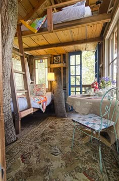 a room with a bed, table and chair in it next to a large window