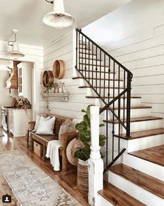 a living room filled with furniture and a stair case next to a wooden floor covered in rugs