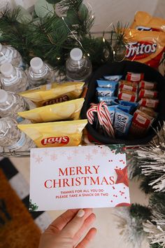 someone holding up a christmas card in front of a table full of snacks and candy