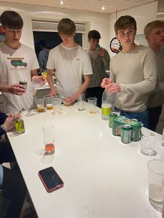 a group of young men standing around a white table with drinks and beverages on it