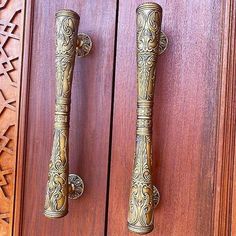 two ornate brass handles on wooden doors with intricate carvings and patterns around them, one is holding a door handle that matches the other