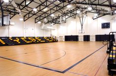 an indoor basketball court with yellow and black lines on the floor, surrounded by lights