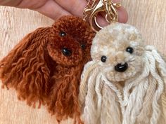 two poodle key chains being held by someone's hand