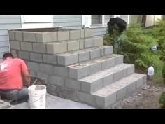 a man is sitting on the steps next to some concrete blocks and painting it with white paint