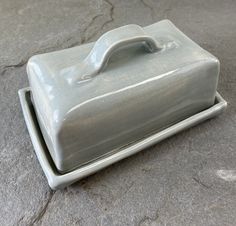 a gray ceramic dish sitting on top of a stone floor