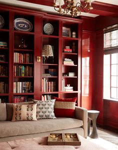 a living room filled with lots of red bookshelves