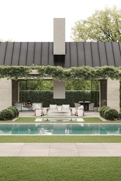 an outdoor living area with a pool and lounge chairs in the foreground, surrounded by greenery