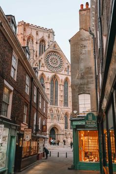 an old church is shown in the background as people walk down the street near it