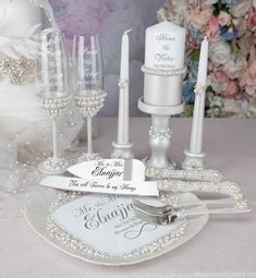 a table topped with white dishes and candles