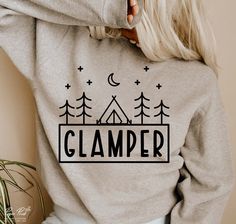 a woman wearing a sweatshirt with the word glamper printed on it and trees