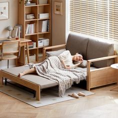 a woman laying on top of a couch in a living room next to a book shelf