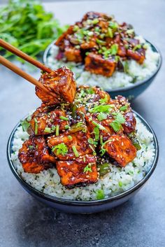 two bowls filled with rice and meat on top of each other next to chopsticks