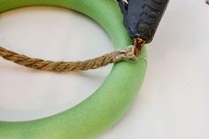 there is a piece of rope attached to the handle of a green ring with scissors on it