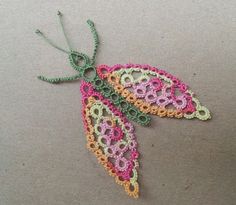 a crocheted butterfly ornament hanging from a string on a gray surface