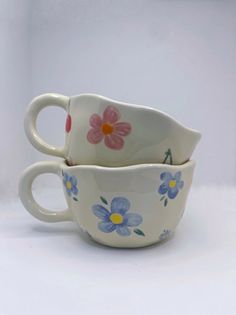 two white cups with blue and pink flowers on them