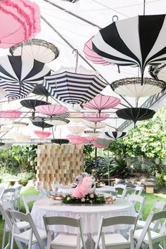 an outdoor dining area with tables and umbrellas hanging from the ceiling over it's grass