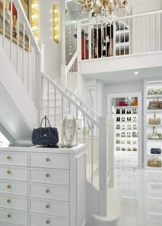 a white closet filled with lots of purses and handbags next to a staircase