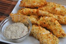 some fried food on a white plate next to a small bowl of ranch dips